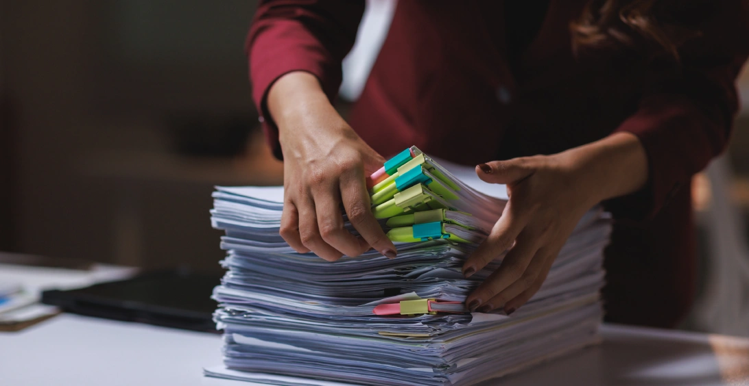 Woman organizing documents pile with sticky notes